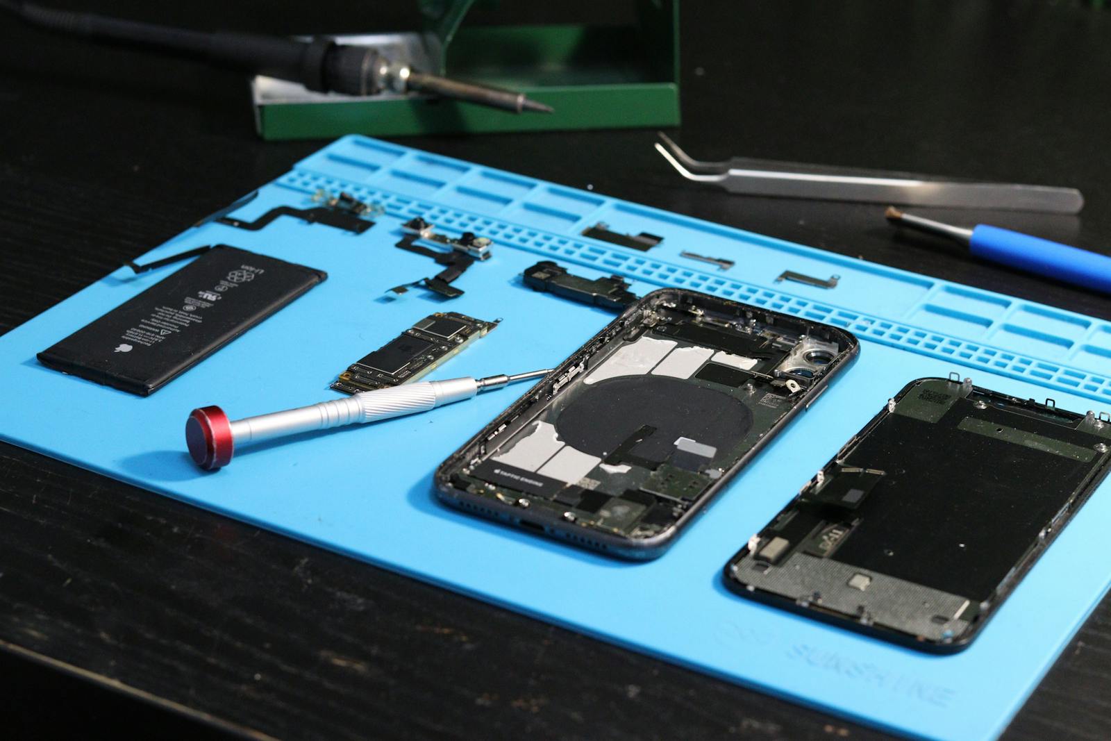 Smartphone-Reparatur: zerlegte Bauteile auf blauer Reparatur-Matte
